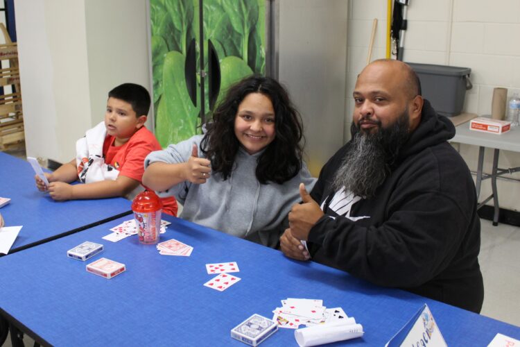 A Cowherd student poses with her family while playing a math card game.