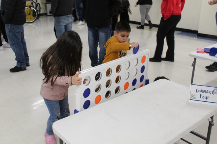 Two young students play giant Connect Four.