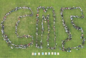 Cowherd Middle School students and staff standing on the field and forming the letters CMS.